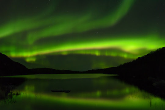 The Aurora in the sky above the hills and the lake.