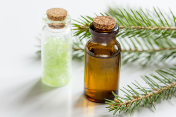 fir branches and spruce bath salt and aroma oil on white table background