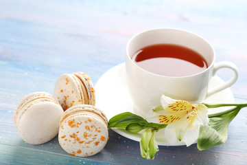 French macarons with alstroemeria and cup of tea on blue wooden table