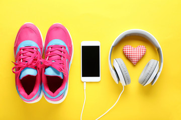 Sport shoes with smartphone and headphones on yellow background