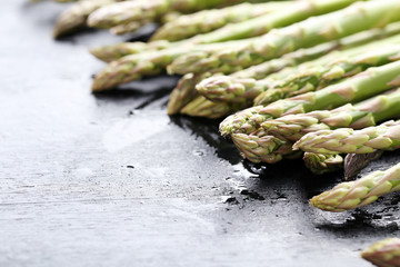 Green asparagus with water drops on black wooden table