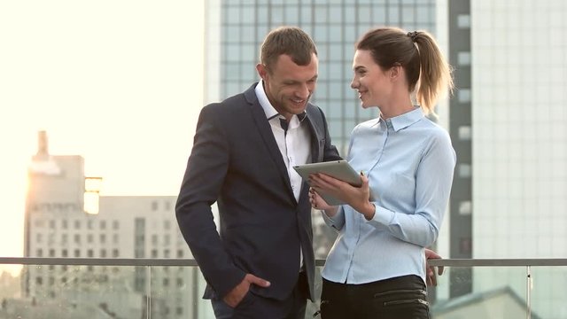 Business people smiling, city background. Man and woman with tablet. Building work relationships.
