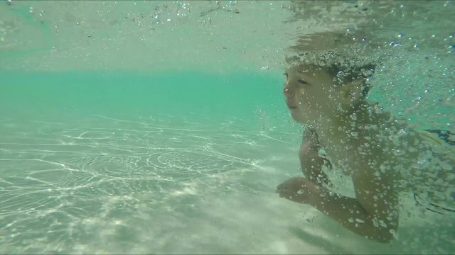 The little boy is swimming under the water in the pool