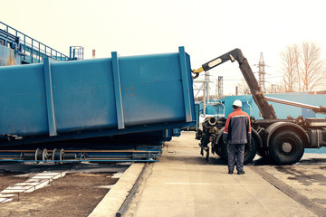 Loading container with waste to a special machine for subsequent transportation to a waste disposal plant. Waste processing plant. Business for sorting and processing of waste. - obrazy, fototapety, plakaty