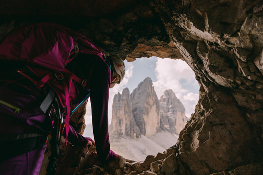 Kletterer schaut aus einer H&ouml;hle vom Paternkofel Klettersteig auf die Drei Zinnen, Italien