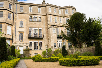 View of a classic Georgian residential building made in golden-coloured Bath Stone, with small garden in the back.