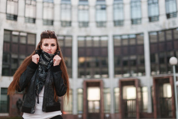 Fototapeta premium Portrait of sexy slim woman dressed in a short white t-shirt , black leather jacket and shorts at the hips. She holds the collar of his jacket.