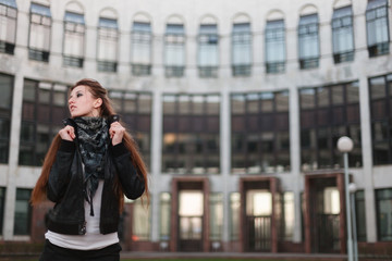 Portrait of sexy slim woman dressed in a short white t-shirt , black leather jacket and shorts at the hips. She holds the collar of his jacket.