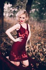 Beautiful and elegant blonde woman with red lips and hair waves wearing wine red nightie posing on...