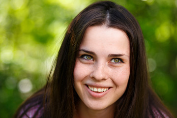 Young beautiful freckled green-eyed woman face with healthy skin and wide smile, close-up portrait