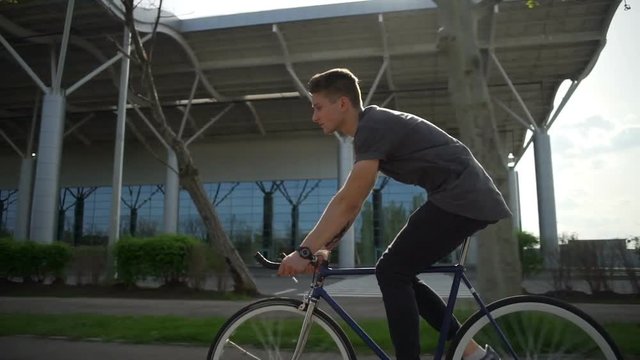 Man riding his bike in front of a big building slow motion