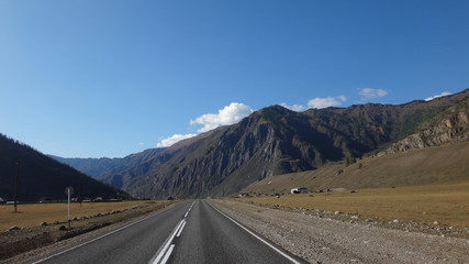 landscape of road in wild field with mountains at horizon