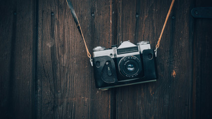 Old gray zenith in a brown leather case hanging on a wooden wall background. - Powered by Adobe