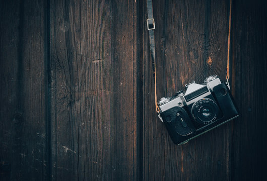 Old gray zenith in a brown leather case hanging on a wooden wall background. - Powered by Adobe