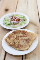 Roti Parata or Roti canai with curry sauce on wooden background.