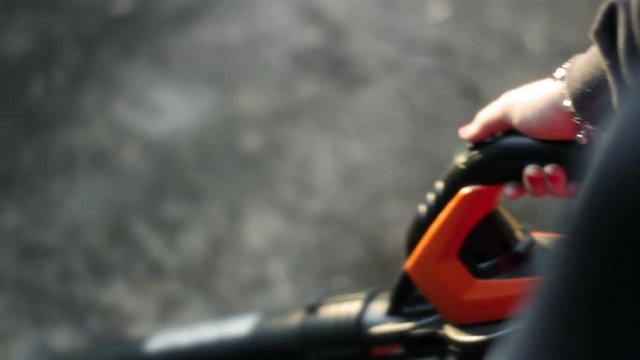 Woman using leafblower on concrete outdoor patio area in spring