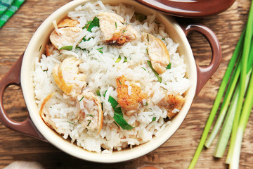 Tasty rice with chicken in saucepan on wooden table