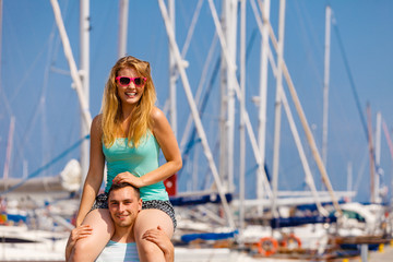 Man giving girlfriend piggyback ride on marina