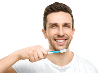 Young handsome man brushing teeth on white background