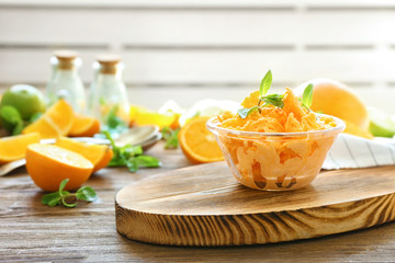 Glass bowl with delicious citrus ice cream on wooden board