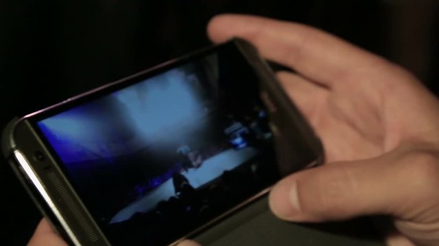 Male watching break-dance battle video on mobile phone, modern technologies