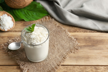 Delicious coconut cream in glass on wooden background