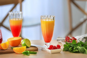 Glasses of Tequila Sunrise cocktail with ingredients on kitchen table