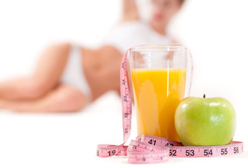 Glass of orange juice with green apple and  measuring tape
