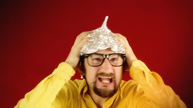 An ugly man wearing a tin foil hat (made from aluminium, worn to shield the brain from threats such as electromagnetic fields, mind control or reading). Conspiracy, pseudoscience, paranoia.
