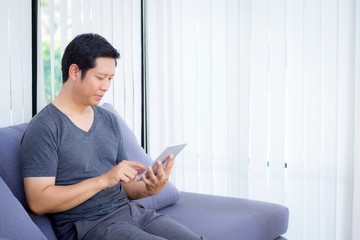 businessman watching media content in a tablet sitting on a sofa at home.