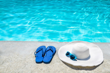 Summer background with hat, flip flops and sunglasses near the pool
