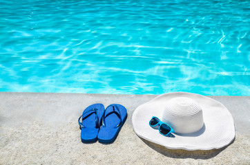 Fototapeta premium Summer background with hat, flip flops and sunglasses near the pool