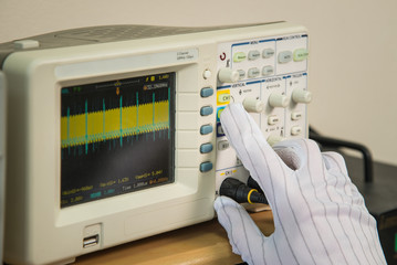 Modern oscilloscope, man's hand adjusting wave signals, closeup