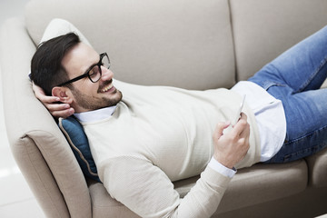 Fototapeta premium Handsome young man with glasses smiling and using phone