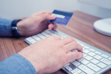 hands holding credit card and a typing on wireless keyboard making online purchase