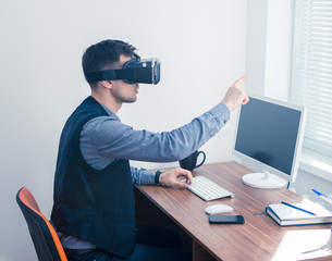 Young businessman in vr glasses drawing chart with gesture. Virtual reality in office