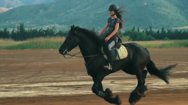 Girl galloping on a horse, a frisian stallion in Spain.