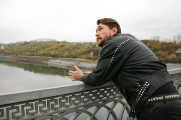 Man in black leather jackets looking at river