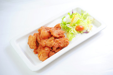 Fried chicken with lettuce and tomatoes slad on white platter