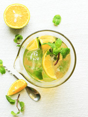 Glass of fresh orange tea with mint leaf on white background