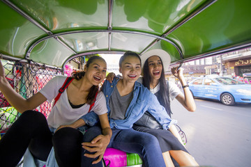 Obraz premium Three asian girls are taking Tuktuk to travel around Chinatown, Thailand