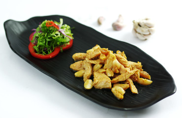 Grilled boneless chicken with garlic and salad on black platter
