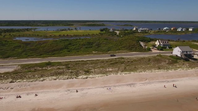 A slowly moving profile aerial view of Topsail Island beach and the Intracoastal Waterway during the day.	 	