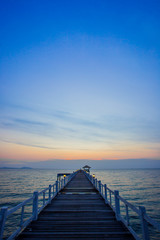 Obraz premium Drewniany most na morzu o zachodzie słońca, Tajlandia.