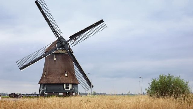 Old windmill in Volendam, Netherlands, over cloudy sky in yellow gras field.
