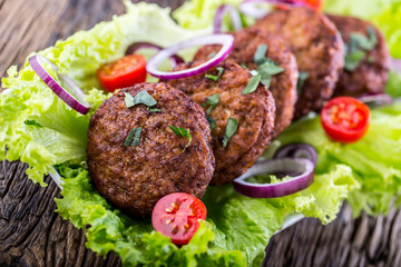 Beef Burgers meatballs cutlets with lettuce salad tomato onion on wooden board. - Powered by Adobe