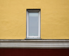 Small window on yellow wall with cornice