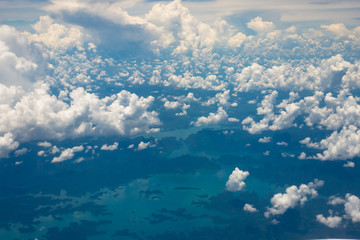 View from plane, clouds floating above sea and island.