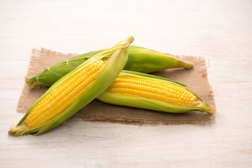 Sweet corns. Fresh corn on cobs on wooden table.
