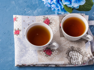 Cup of tea on blue background with flowers and textile